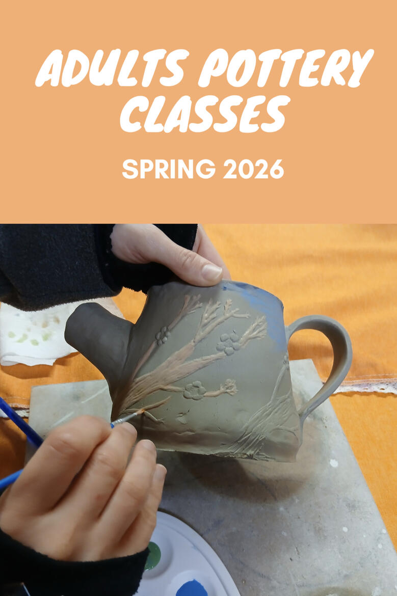 A hand painting a clay teapot during a pottery class