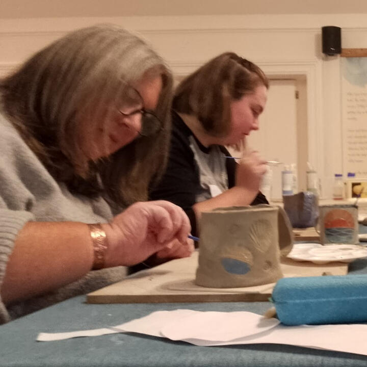 Close up of a child's hand while painting a ceramic imprint of their own hand