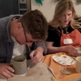 Close up of a child's hand while painting a ceramic imprint of their own hand